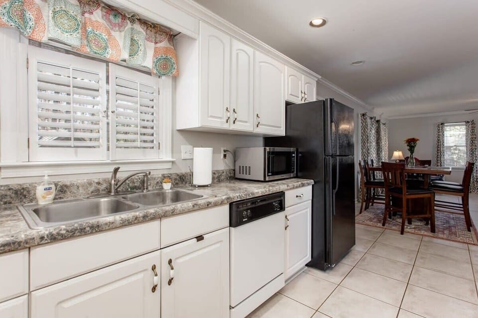 Bright sun comes in the kitchen window overlooking driveway and woods area.