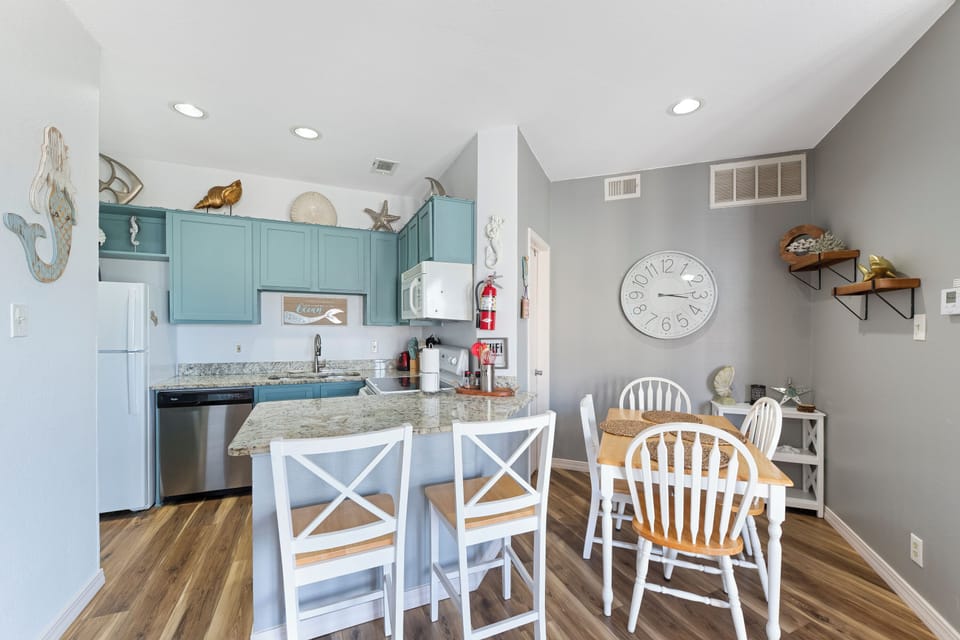 Your charming coastal kitchen features teal cabinets and granite counters, perfect for preparing beachside meals together.