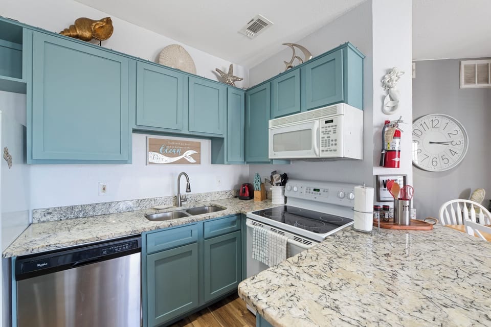 Your coastal-themed kitchen awaits with sea-green cabinets, granite counters, and full appliances for preparing memorable vacation meals.