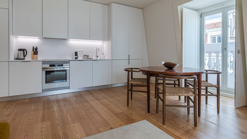 Gather around for breakfast or evening meals in this sleek dining space with a fully equipped kitchen and timeless design. #ModernKitchen #OpenPlanLiving #HolidayRental #LisbonHomes #Portugal #PT #Lisbon