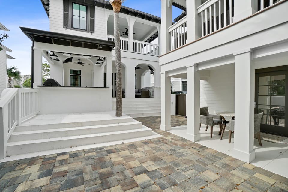 Elegant coastal architecture frames this welcoming outdoor space where you can unwind on beautifully paved terraces beneath graceful white columns and covered porches.