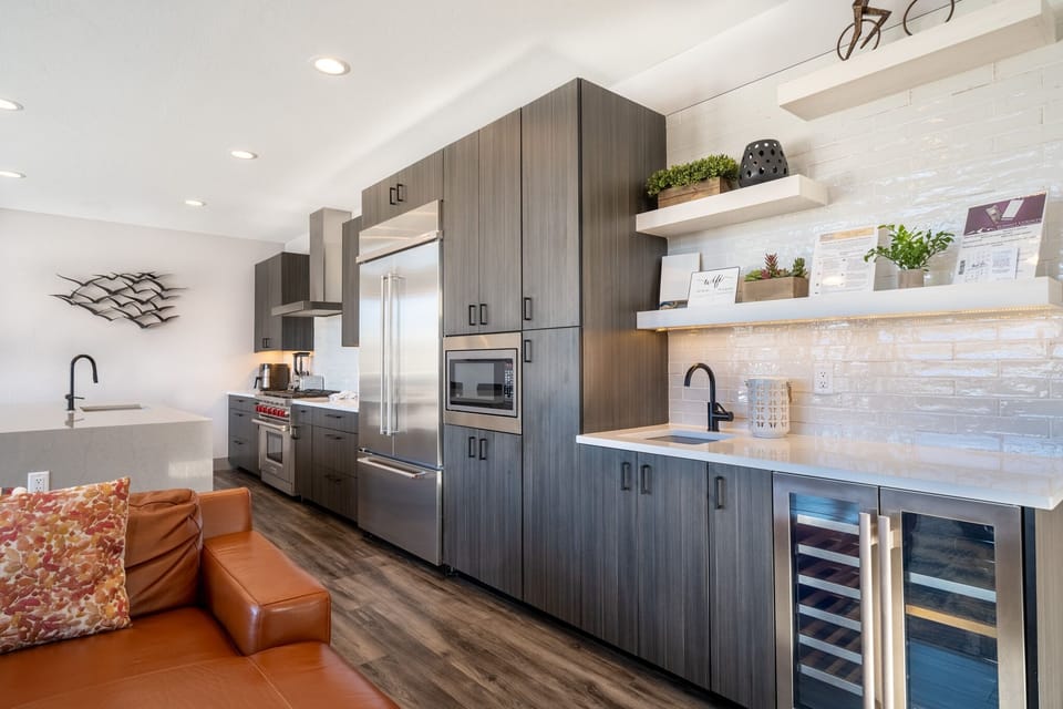 Your modern kitchen features sleek appliances, marble counters, and floating shelves—perfect for preparing meals and gathering with loved ones in sophisticated style.