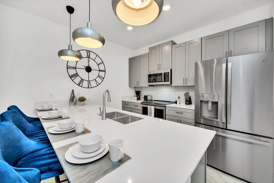 Polished kitchen of the townhouse in Kissimmee Florida - Well-lit workspace with strategically placed task lighting - Integrated appliances for a seamless and stylish appearance - Breakfast bar and high chairs