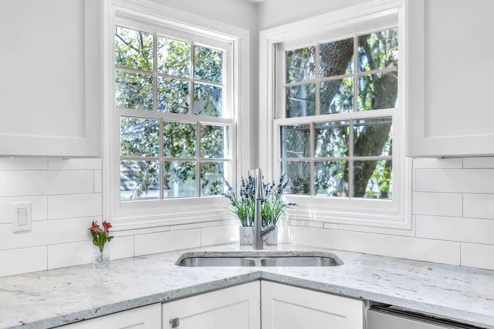 corner kitchen sink with large windows offering natural light and garden views