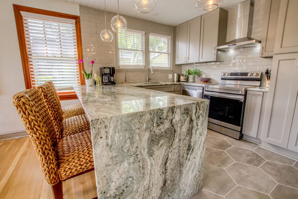 Waterfall granite island offering seating for three for breakfast, work, etc.