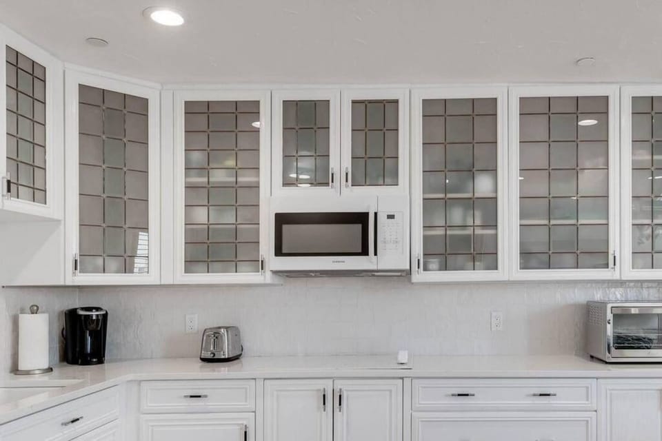 Fully stocked kitchenette with glasses, microwave, Refrigerator, Keurig coffee maker, glasses, plates, and cutlery