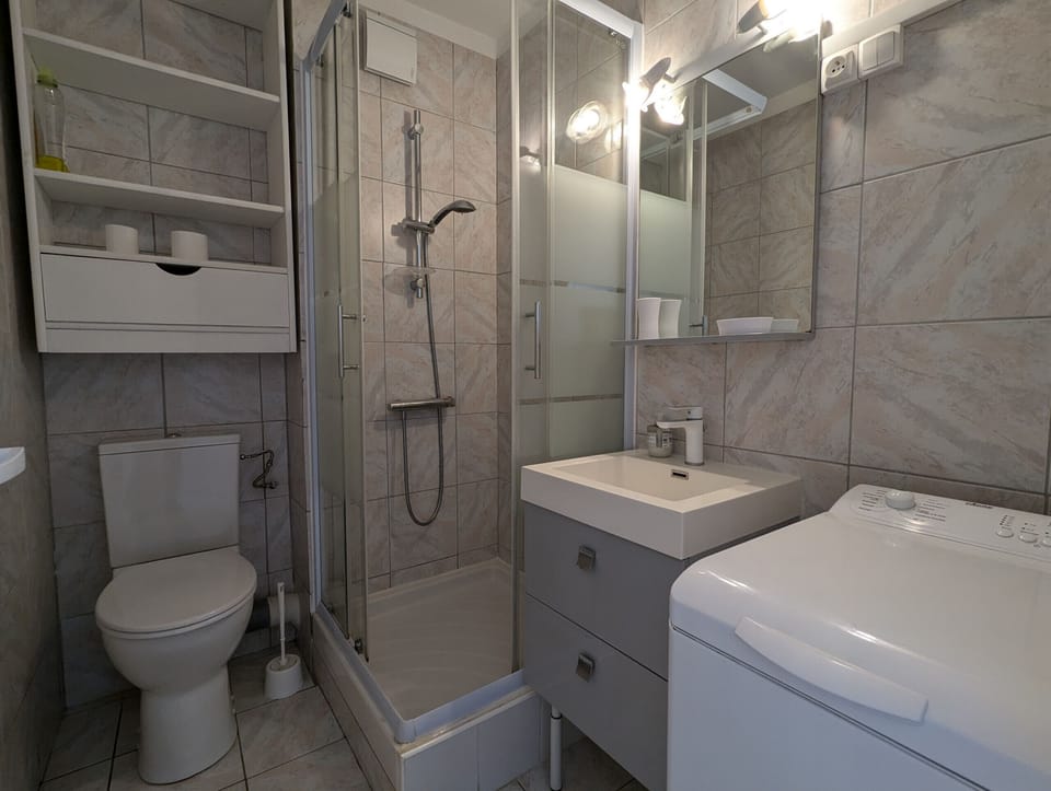 Practical and equipped bathroom with toilet, storage, washing machine and shower cabin