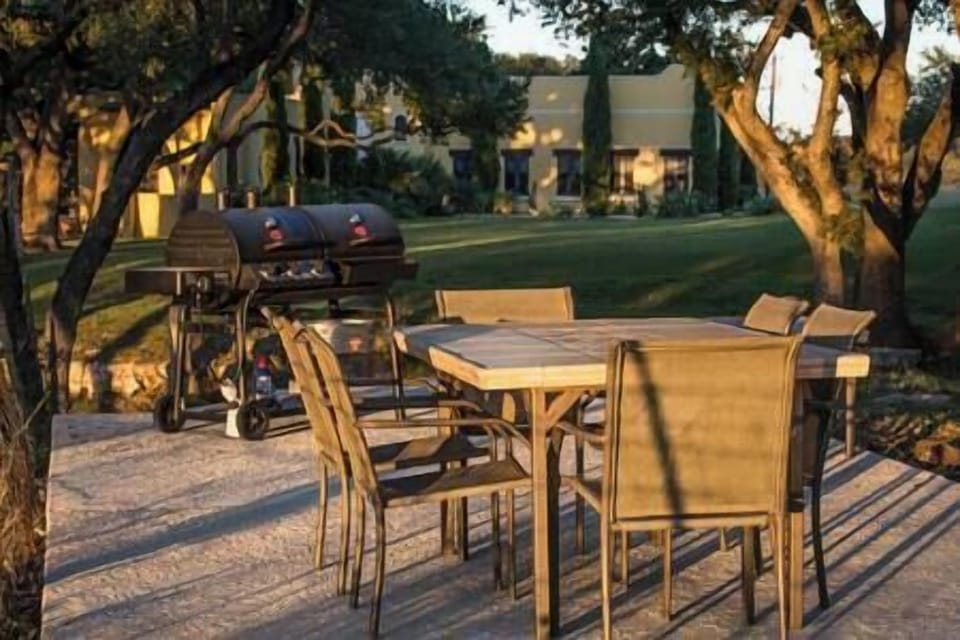 Guest patio overlooking river with propane/charcoal grill, table and swing set.