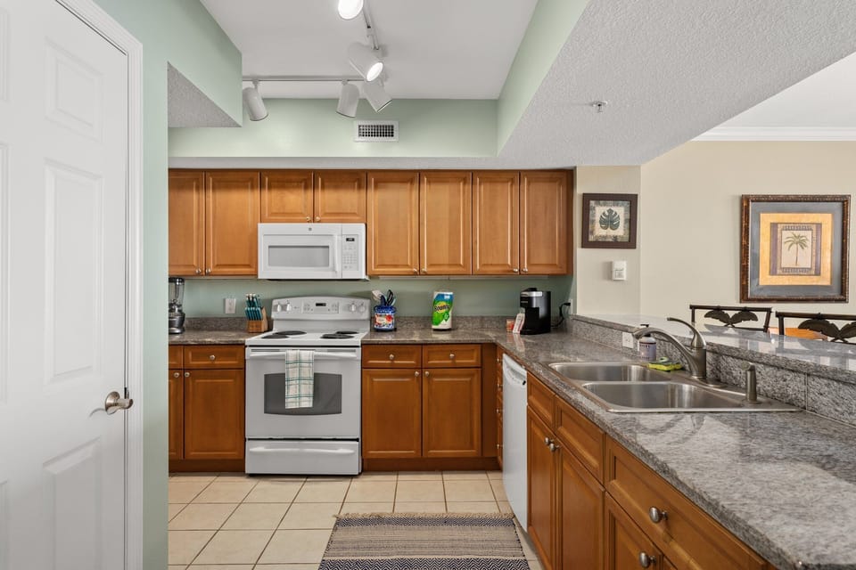 Fully-stocked kitchen, with pots, pans, blender, coffee maker, dishes, cups, mugs, and silverware