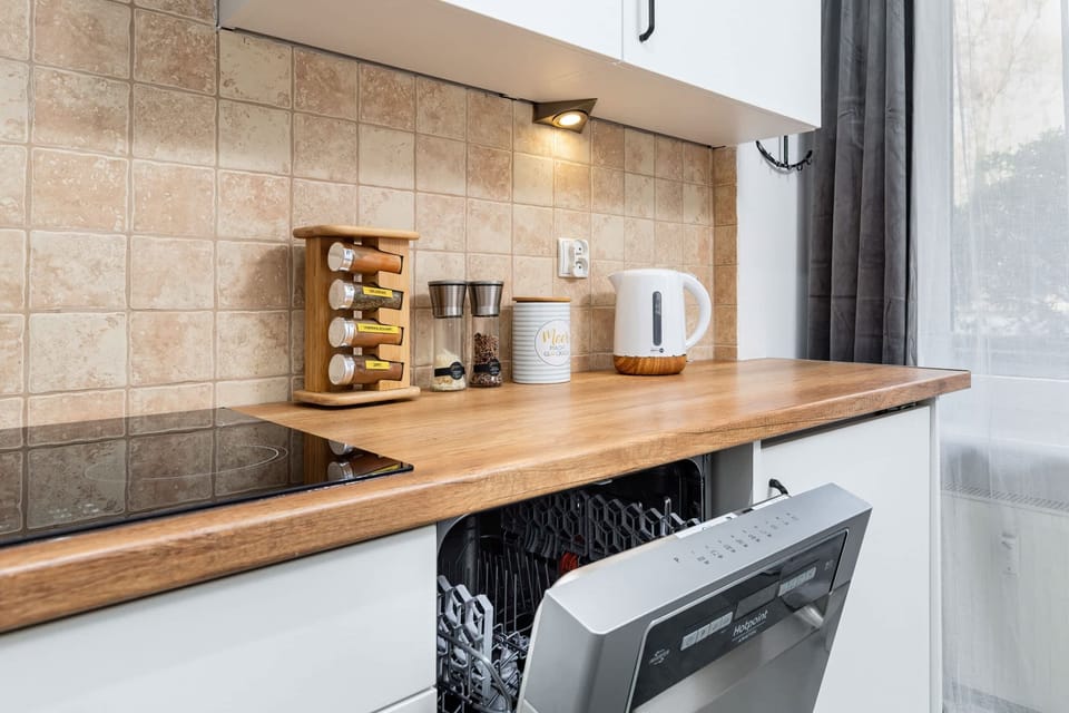 A well-equipped kitchen with white cabinets, wooden countertops, and modern appliances.
