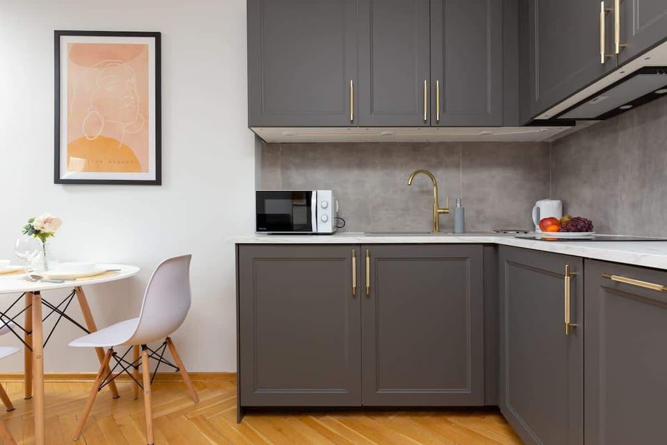 A compact yet functional kitchen with gray cabinets, a tiled backsplash, and modern appliances.
