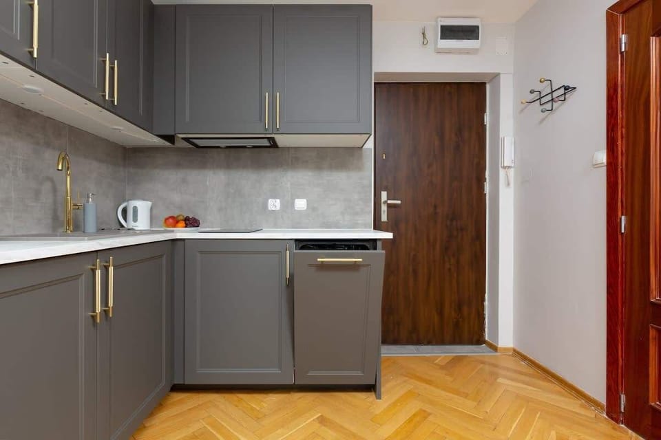 A modern kitchen with sleek gray cabinetry, a tiled backsplash, and ample storage space.
