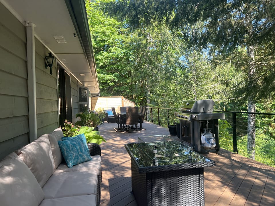 Large deck with multiple seating areas overlooks creek