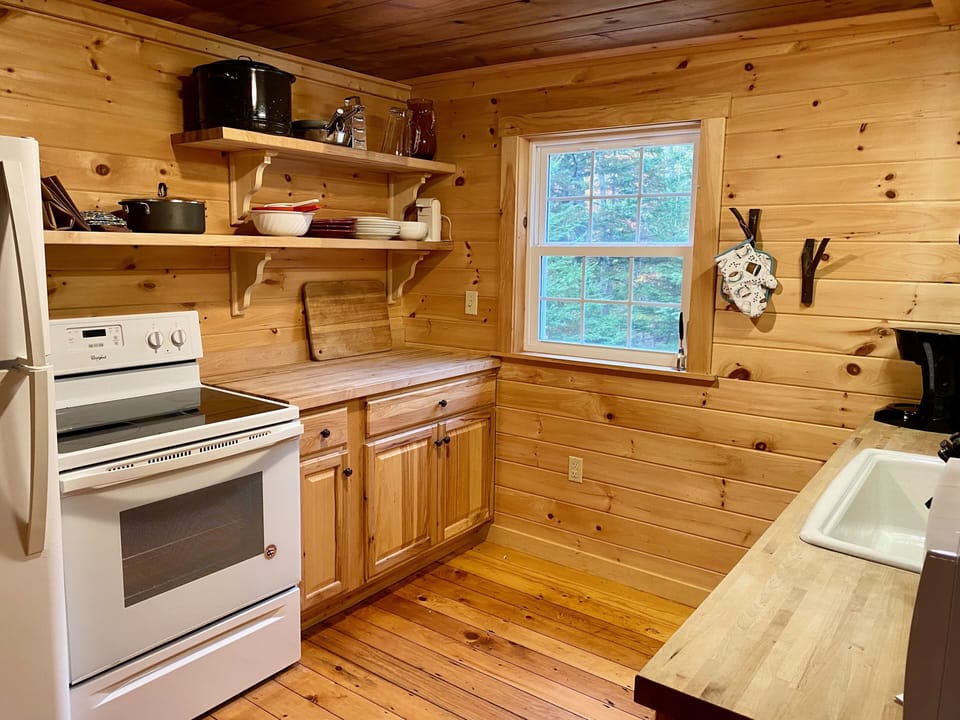 Kitchen with fridge, electric stove, dishwasher, cookware, and microwave. 