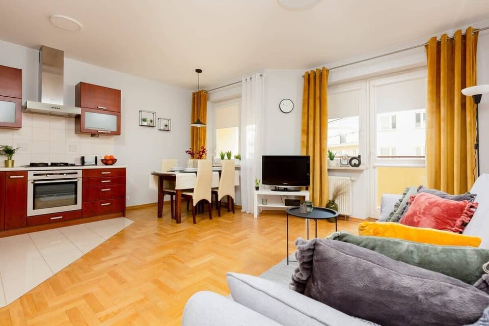 A combined living room and kitchen area with a large sofa and bright red cabinetry. The open layout is ideal for entertaining.