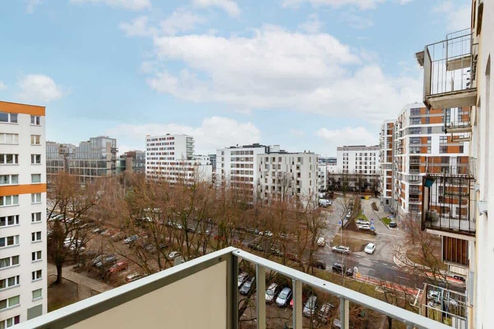  The balcony offers a scenic view of the surrounding residential area, with tall apartment buildings and trees creating a peaceful urban landscape.