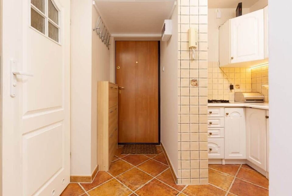A tiled corridor leading to the kitchen, featuring bright lighting and wooden finishes for a warm vibe