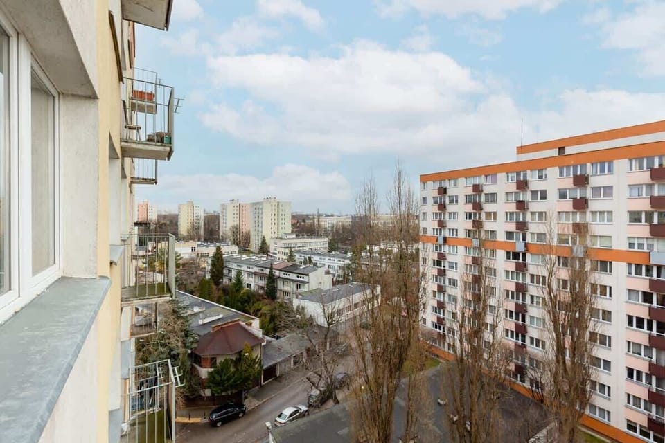 A different angle of the balcony, overlooking a residential area with tall apartment buildings surrounded by greenery.