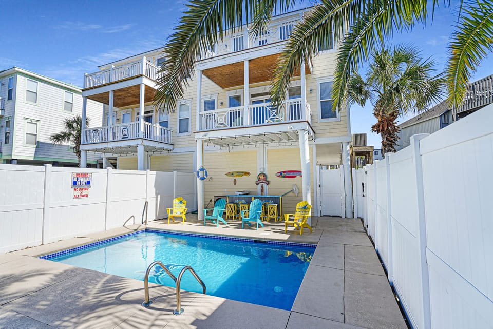 Step into your private pool oasis framed by swaying palms and colorful patio seating, where sunny afternoons unfold beneath a tropical canopy.