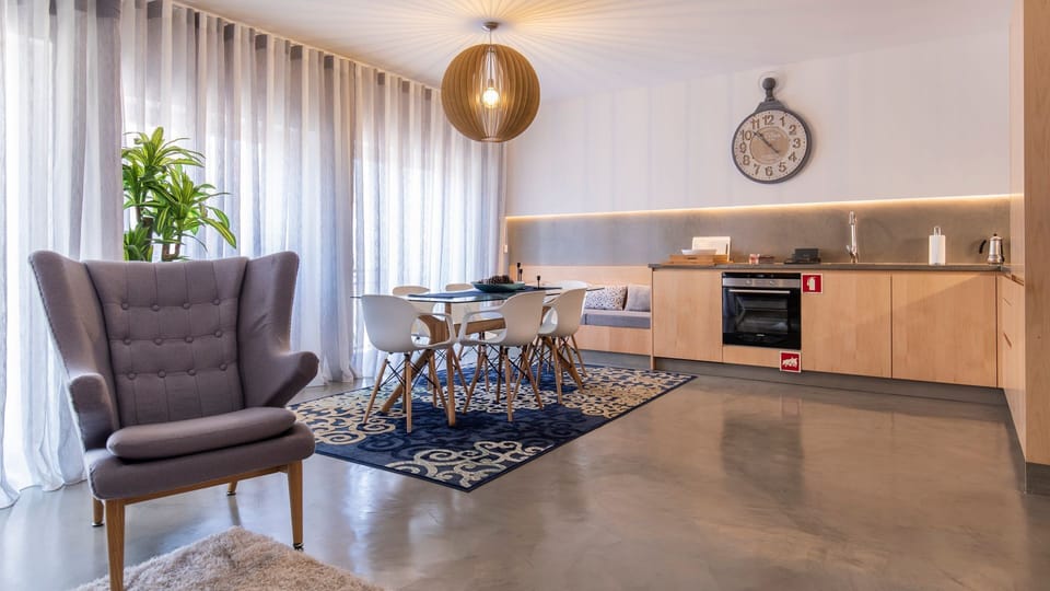 Gather around the sleek dining table in this spacious open-plan living area, where natural light streams in through large windows and a well-appointed kitchenette awaits your culinary creations. Relax in the plush armchair after a day of city adventures.