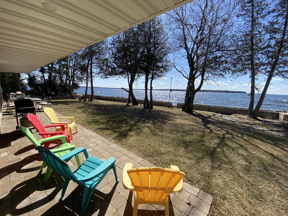 Views from the massive covered porch overlooking yard, fire pit, and waterfront