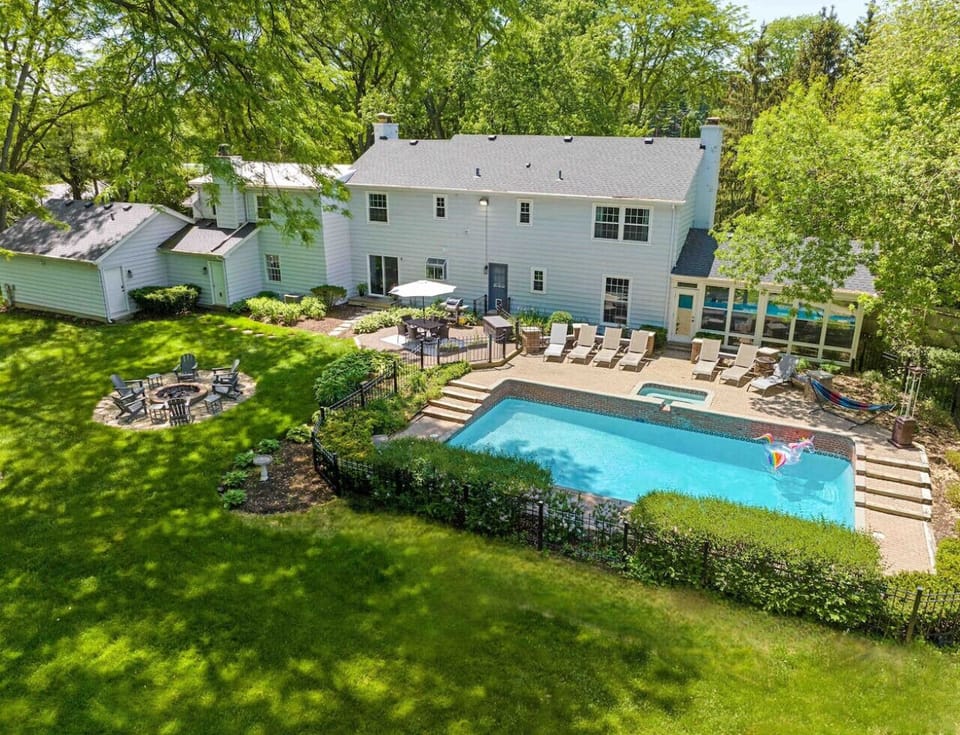 This aerial view showcases the stunning home, situated on over an acre of land, featuring a private heated saltwater pool, spa, and fire pit