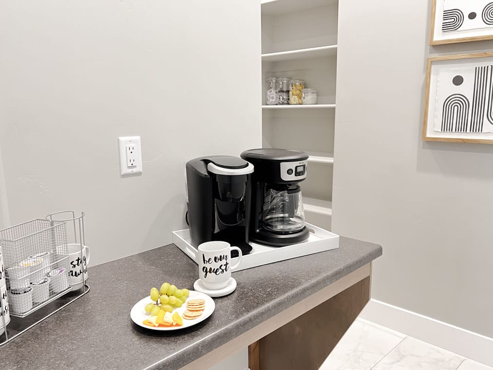 The coffee bar is fully stocked with filters, sugar, creamer, and coffee pods.
