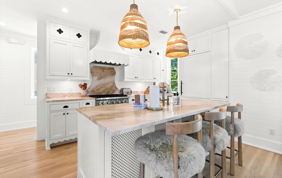 Step into your coastal dream kitchen with stylish woven pendant lights, gleaming marble countertops, and chef-grade appliances ready for your culinary adventures.