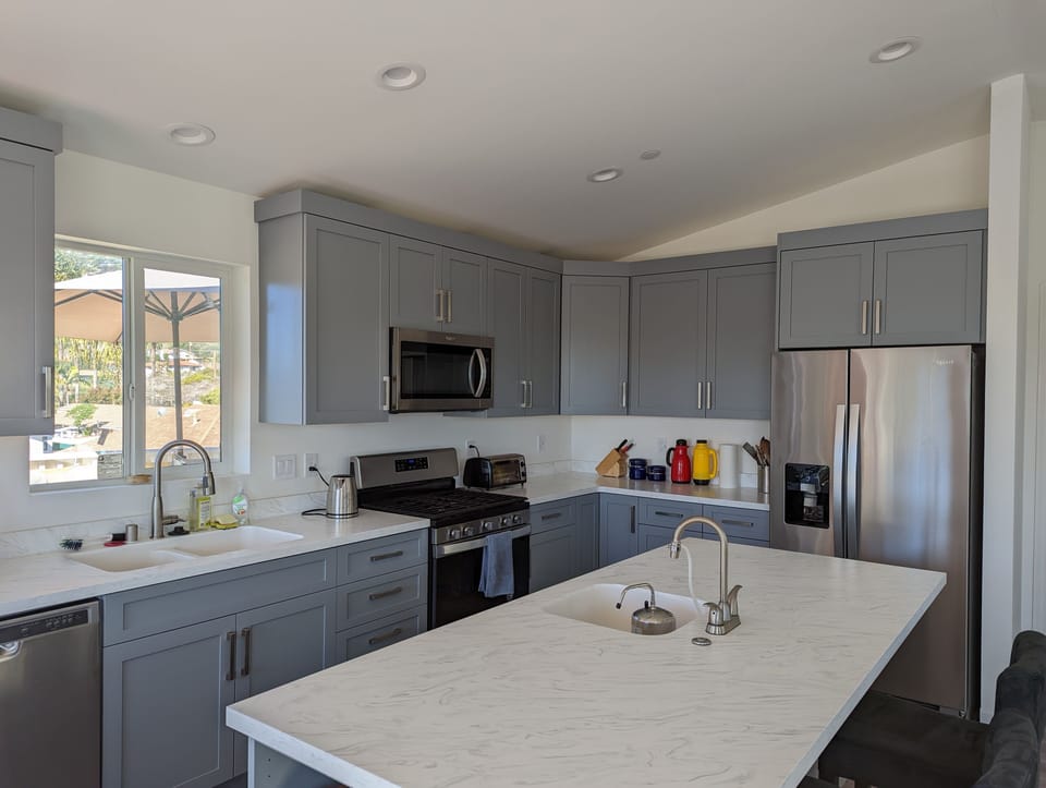 Full kitchen with central island with 2nd sink with white countertops.