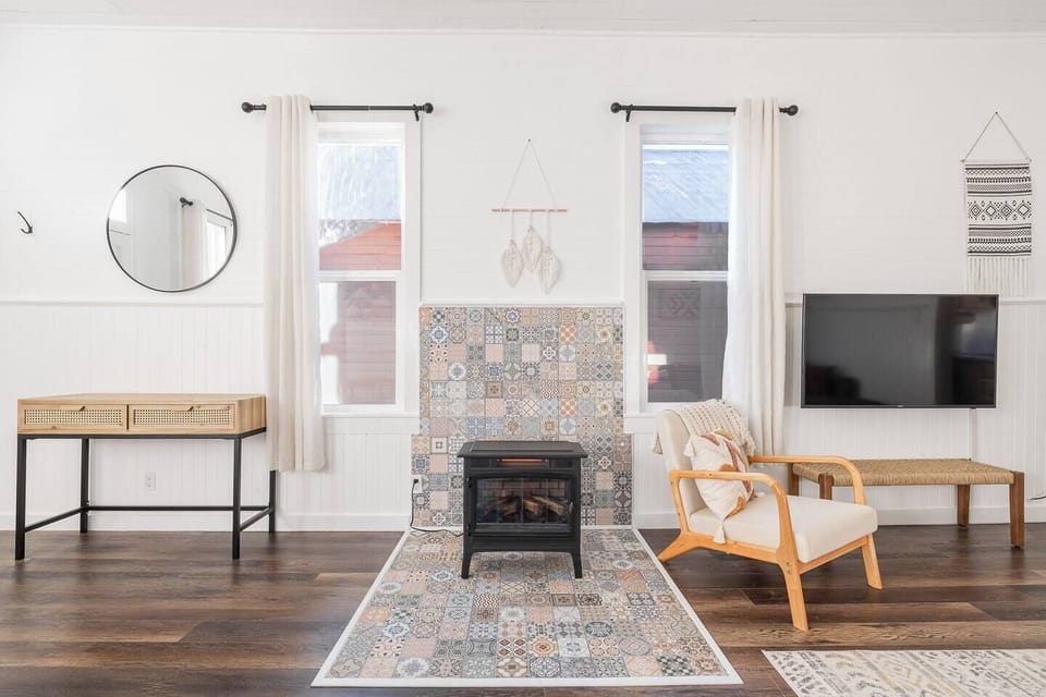 A freestanding electric fireplace sits atop the eclectic mosaic tiles in the main living space. 