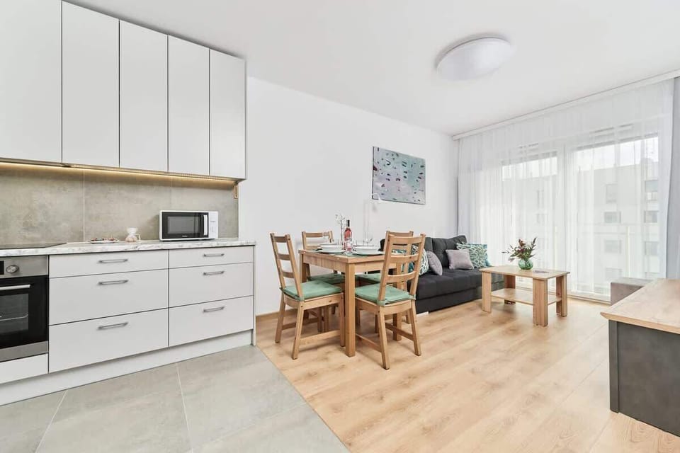 A kitchen and living room area with a dining table, white cabinetry, and a well-organized open layout.