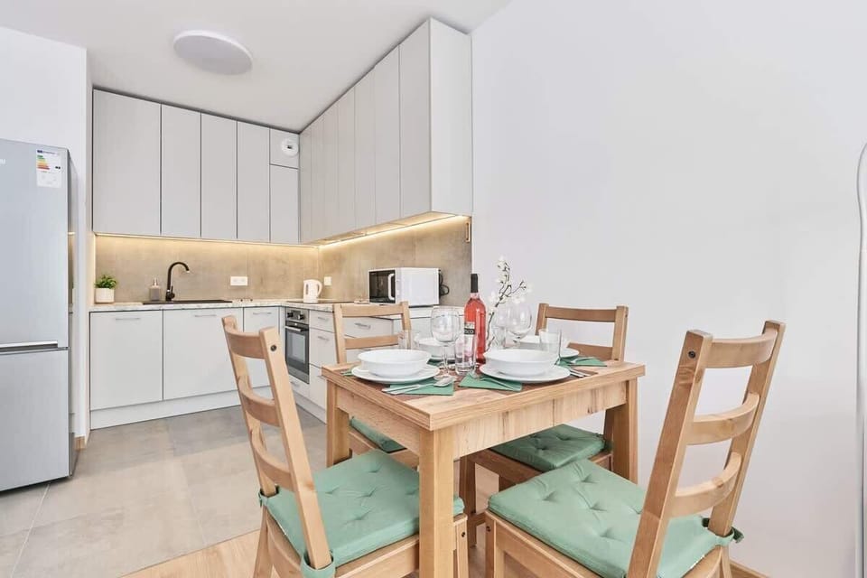 A dining area connected to the kitchen, featuring a table set for meals with wooden chairs and a modern aesthetic.
