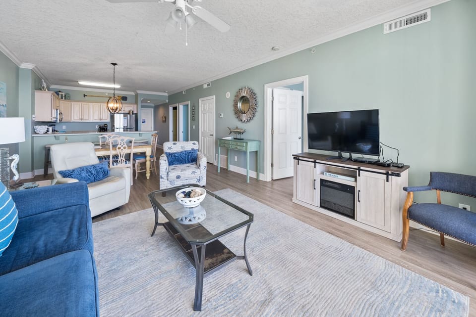 Relax in your spacious living area featuring calming coastal blues, modern amenities, and an open layout connecting seamlessly to your fully equipped kitchen.