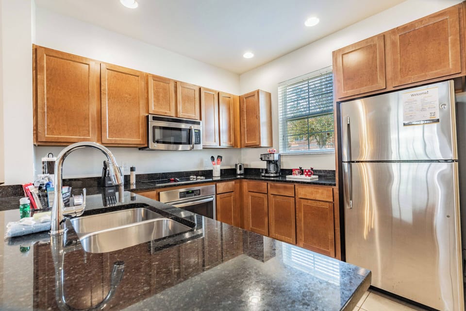 Welcome to a beautifully designed kitchen with elegant wooden cabinetry and granite countertops, ideal for family meals. Bask in the natural light pouring in, enhancing the modern appliances and warm, inviting ambiance.
