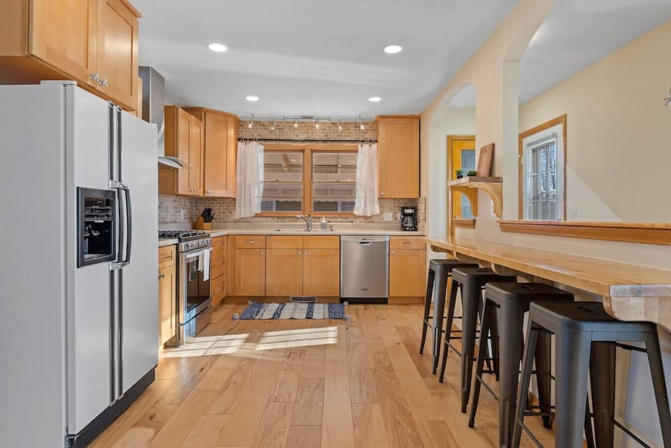 We have a completely equipped kitchen with a refrigerator, stove, dishwasher, and four kitchen bar stools adjacent to the living room.