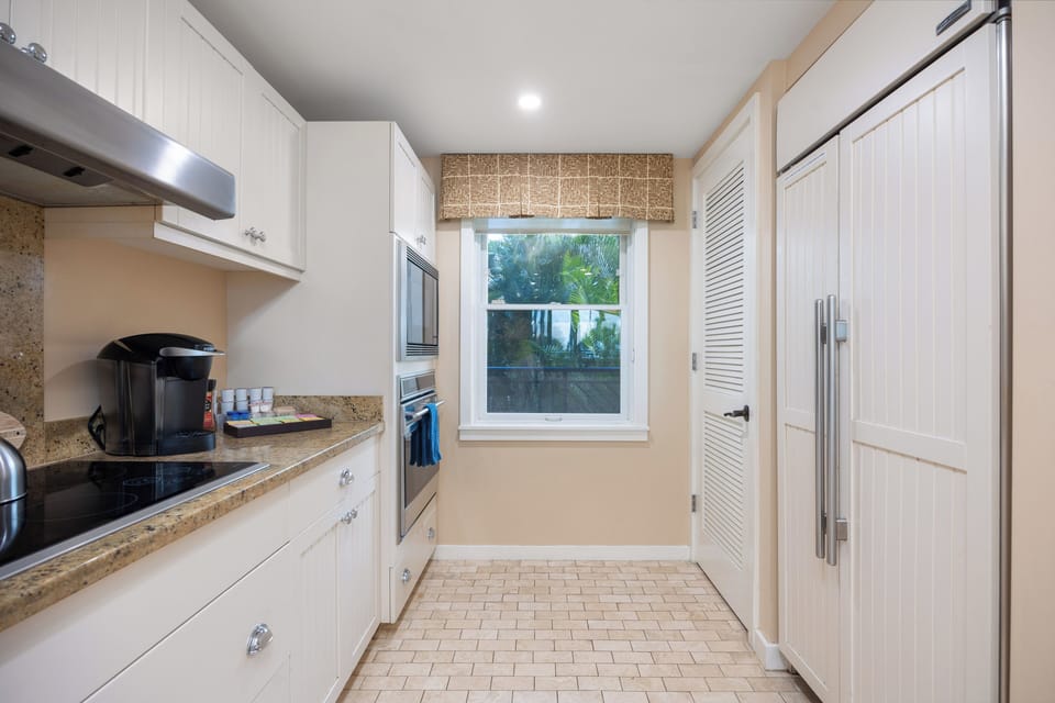 Modern kitchen with granite counters and a view of lush greenery!