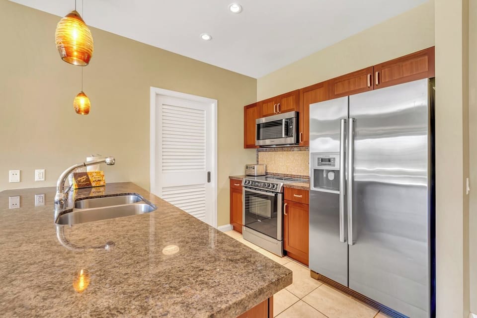 Granite countertops and stainless steel appliances in gourmet kitchen space.