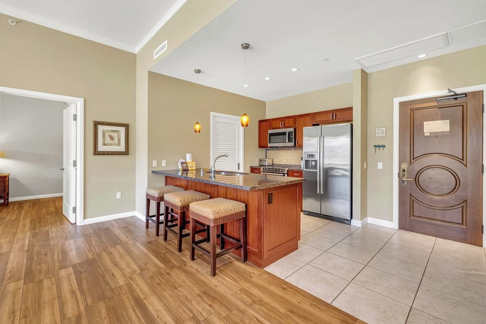  Warm, modern kitchen with island seating and stainless steel appliances.