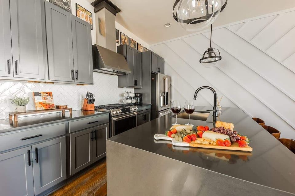 Fully equipped kitchen with stainless steel appliances, and breakfast bar seating with bar stools.