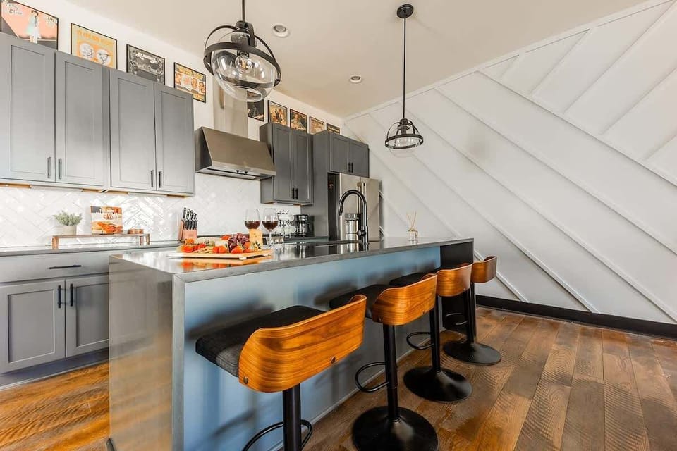 Fully equipped kitchen with stainless steel appliances, and breakfast bar seating with bar stools.