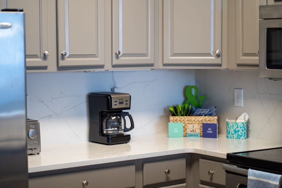 Start your mornings right with a cup of freshly brewed coffee in this bright, fully-equipped kitchen featuring modern appliances and elegant cabinetry.