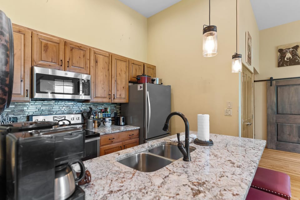 Prepare your favorite meals in this fully-equipped kitchen featuring granite countertops, stainless steel appliances, and warm wood cabinetry.
