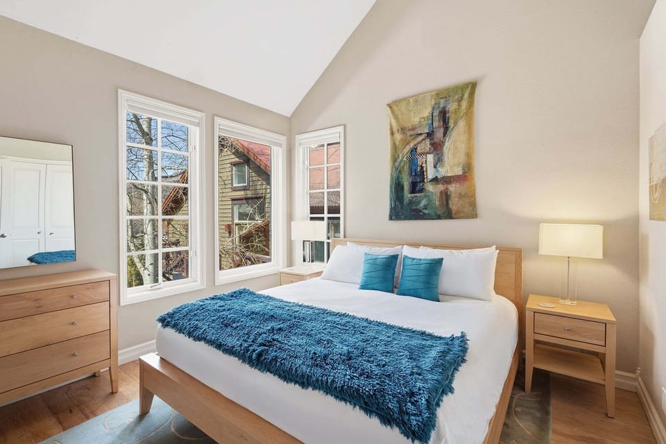 Guest bedroom with queen bed and views from windows.