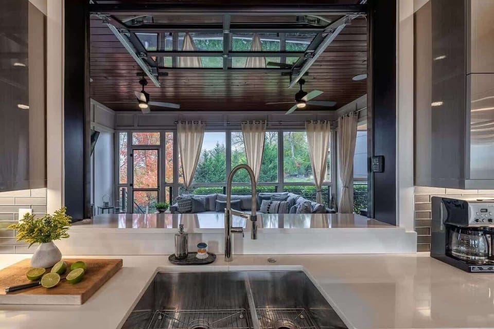 A grand rolling window seamlessly connects the kitchen to the screened-in patio, blending indoor and outdoor spaces.