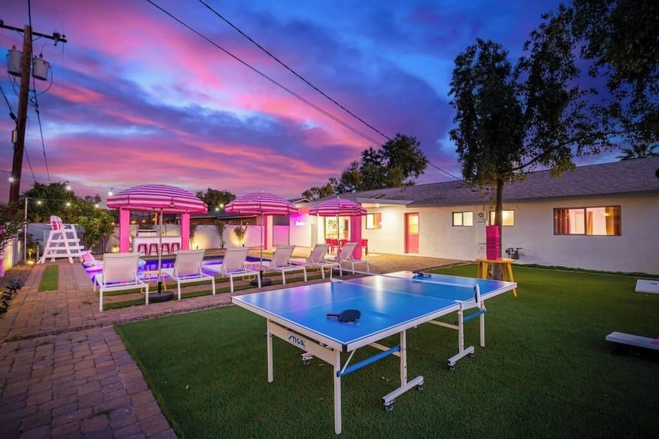 The backyard features yard games, tons of lounging spaces, a heated pool, a built-in grill and outdoor mini fridge, a large outdoor dining area, brand new turf, & a lifeguard chair! Pose for an epic picture on the lifeguard chair next to the mural!