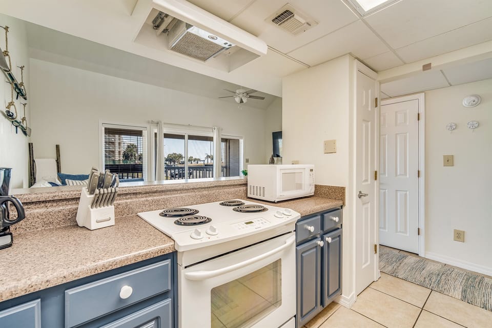 Full kitchen view — navy lower cabinets, updated countertops, and complete appliances. Sand Dollar 206 East, Pensacola Beach loft condo rental.
