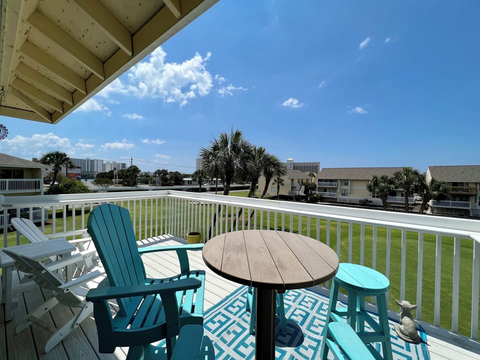 Sip your morning coffee on this sunny deck overlooking tropical palms and open green space, with comfortable seating perfect for relaxation.