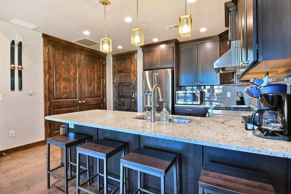 Prepare meals in a fully equipped chef's kitchen featuring high-end Viking stainless steel appliances, sleek quartz countertops, and a large island with seating for four.