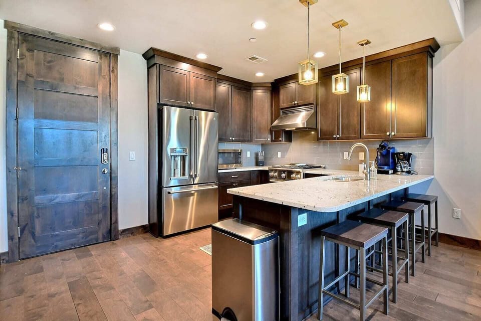 Prepare meals in a fully equipped chef's kitchen featuring high-end Viking stainless steel appliances, sleek quartz countertops, and a large island with seating for four.
