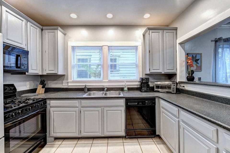Modern and sleek kitchen with white cabinets, black appliances, and a spacious island, creating the perfect space to cook and entertain in style.